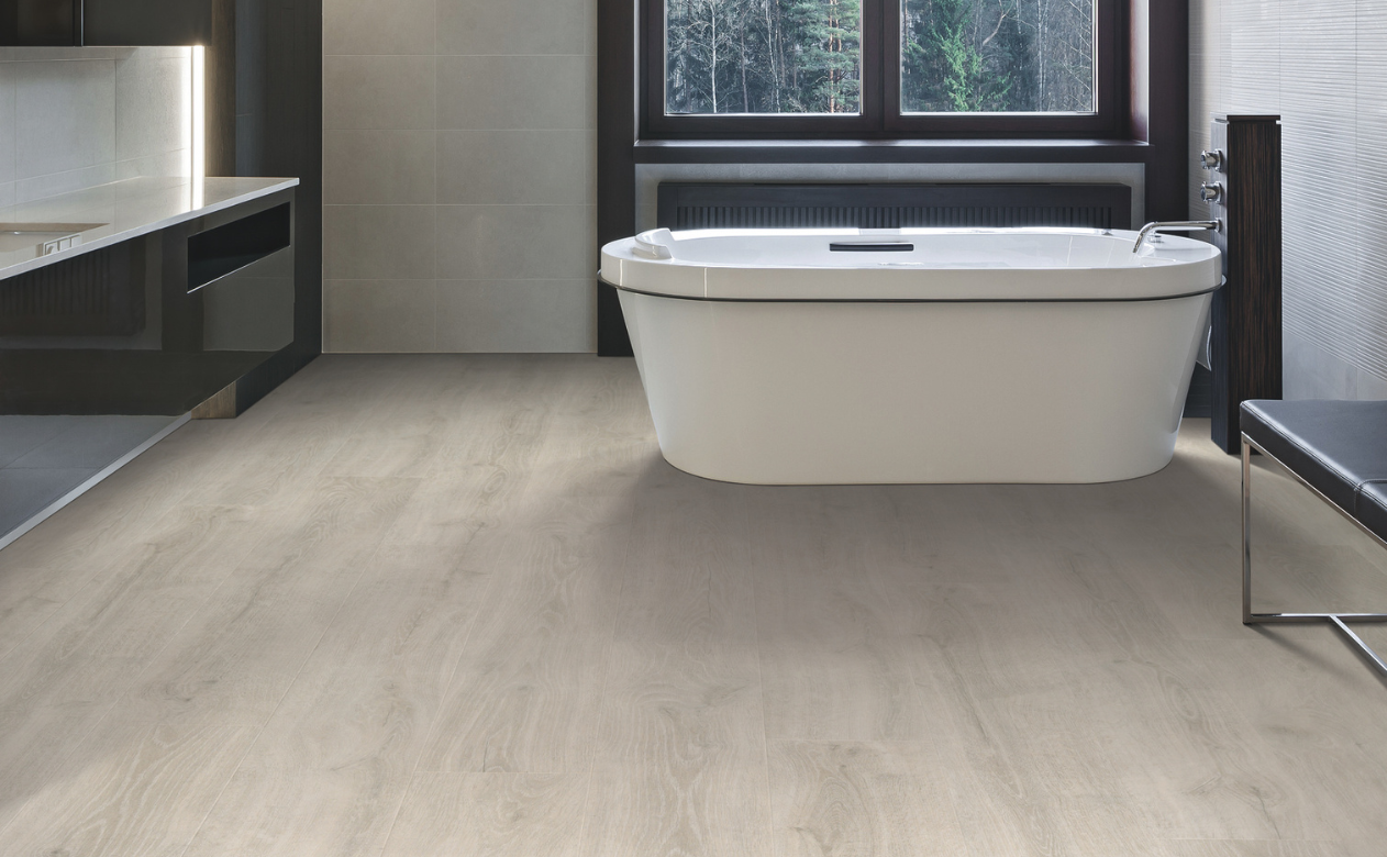 Laminate flooring in a bathroom with light wood-look laminate floors and a bathtub